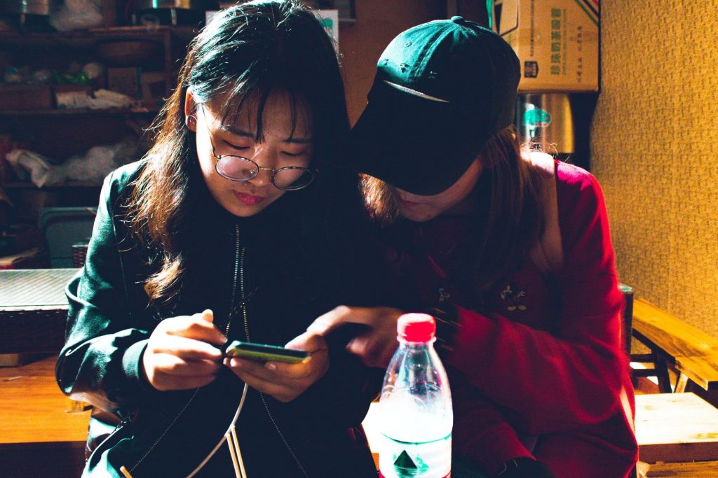 Two award-winning women in Hong Kong are engrossed in digital marketing while looking at a cell phone. Two award-winning women in Hong Kong are engrossed in digital marketing while looking at a cell phone.