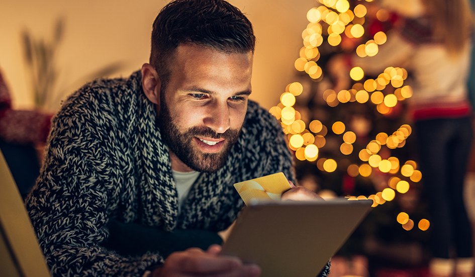 A man in Hong Kong looking at a tablet in front of a Christmas tree. A man in Hong Kong looking at a tablet in front of a Christmas tree.