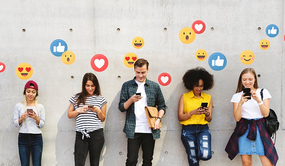 A group of people utilizing digital marketing techniques to capture award winning emojis on their phones in front of a wall. A group of people utilizing digital marketing techniques to capture award winning emojis on their phones in front of a wall.